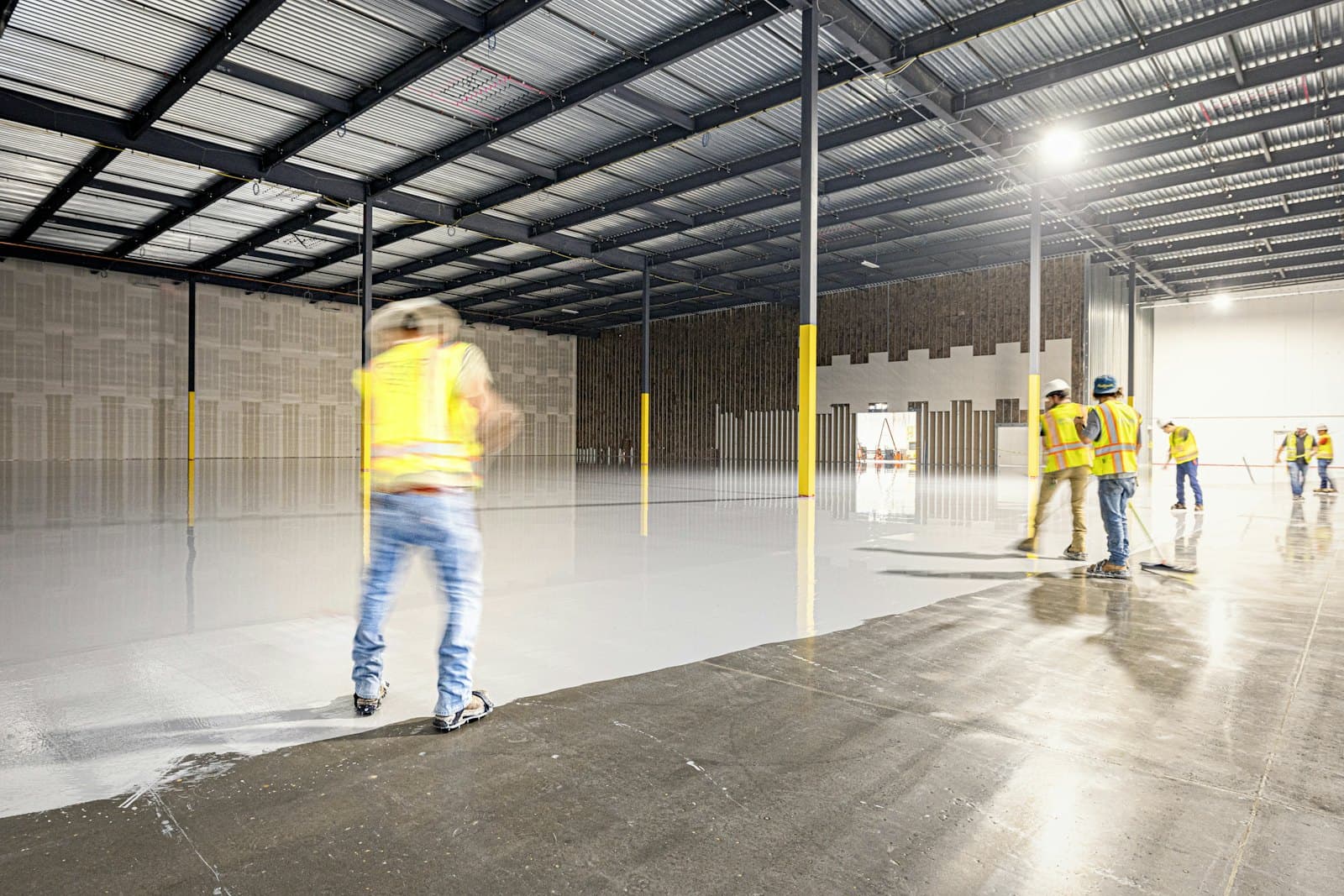 Crew walking a large warehouse with a smooth, level polished concrete floor